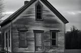 black and white image of beat up looking old house, slight sinister