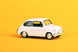 A miniature Volvo car on a yellow background