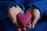 Person in blue sweater holds a pillow heart as a gift that reads “love.” https://www.amazon.com/Some-Assembly-Required-Organ-Transplant/dp/1684337364