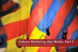 A bright hot air balloon of yellows, reds and blues behind over the ear headphones that hang from above.