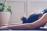 woman with forehead on yoga mat and arms outstretched