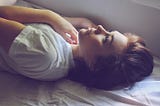 Woman lying in bed, staring up at the ceiling.