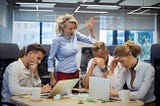 Angry woman boss berating her employees in a meeting