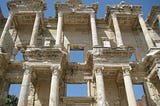 photo of Celsus Library at Ephesus (now part of Selcuk, Turkey), view from ground looking up at the columns and ceiling of ruins, sunny day clear skies