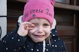 Crying girl wearing a pink hat