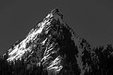 A black & white image of snowy, lone mountain.