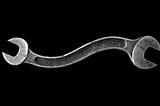 A double ended silver wrench that is curved in the middle, against a black backdrop