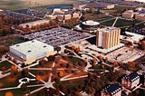 Aerial view of Bowling Green State University which includes Carillon Park (which I don’t believe was called that when I went to school there) in the foreground, with its array of sidewalks, Anderson Arena (now Memorial Hall) , Jerome Library, Saddlemire Student Services Building (a disc-shaped building), Moore Musical Arts Center, the Student Recreation Center, and part of the Kreischer Quadrangle (student housing).