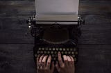 Person’s hands typing on a vintage typewriter