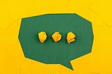 Green speech bubble made of paper mache on a yellow background