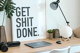 Working desk with laptop with a “Get shit done” poster