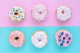 Photo of assorted donuts on a pink and light blue background.
