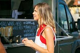 Young woman choosing food at street food counter