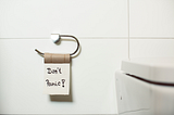Empty toilet paper roll with sticky note that says, “Don’t Panic!”