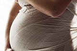 Pregnant woman holding her belly swaddled in cloth