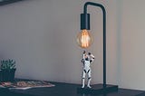 A small storm trooper toy looking up at a light bulb