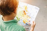 Boy standing while reading map.