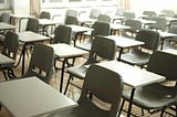 An empty classroom is filled with empty desks and chairs.