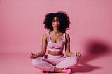 Girl meditating in pink outfit, in a pink background