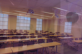 Picture of a university classroom..faintly can see the side view of instructor (author) at the front of the classroom
