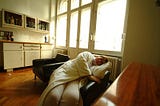 woman wearing robe and pajamas sleeping sideways in a chair