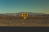 A single direction sign pointing in both directions, set against a barren landscape.