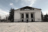 Image of the Donetsk Academic Regional Drama Theatre in Ukraine, destroyed by the Russians in 2022, with the Russian word for “children” written in front of it in large, white Cyrillic letters.