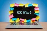 An open laptop surrounded by sticky notes with the words “UX Who?” typed on the screen.