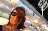 Red haired woman on a Catamaran, sunglasses, truthful face