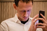 Blind man listening to mobile navigation on a smartphone.