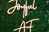 A light sculpture with the words “Joyful AF”