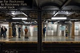 An photograph of people waiting at a subway station in New York