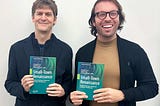 two men holding copies of a book they wrote