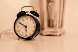 Rounded clock on a table with hour hand at 6 and minute hand at 10.