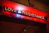 Red-lit marquis with neon text “LOVE & RESISTANCE” over white text reading “Stonewall 50”