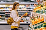 Woman wearing a surgical mask and holding fruit in a supermarket