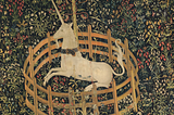 Medieval tapestry of a unicorn kneeling inside a very small fence, surrounded by elaborate flowers and plants.