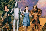 Cast photo of the Scarecrow, Tin Man, Dorothy, and the Lion on the Yellow Brick Road to the Land of Oz