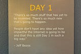 A plaque mounted on a wall with the heading “DAY 1” in bold orange text. Below it is a quote from Jeff Bezos that reads: “There’s so much stuff that has yet to be invented. There’s so much new that’s going to happen. People don’t have any idea yet how impactful the Internet is going to be and that this is still Day 1 in such a big way.”