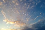 Picture of a deep blue sky with orange, pink and white fluffy clouds