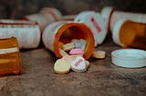 An overturned prescription bottle spills colorful heart-shaped candies writing xoxo on