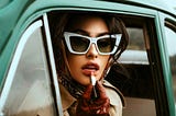 Woman reapplying lipstick, wearing sunglasses