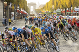 A peloton of cyclists rides through a road and the Arc de Triomphe in the background.