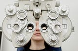 A subject behind a “phoropter” used to determine the refractive power of each eye and the possible need for glasses