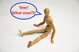 A wooden mannequin sits on the floor, legs outstretched. His speech bubble reads: “Yow! What now?!!”