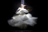 A dancer in a white dress dancing with blurred movement