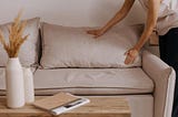 A person setting the living room sofa cushions to organize home.