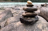 Inukshuk built of round stones near a river.