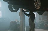 A mechanic carrying out a repair on a car in a dusty garage