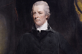 William Pitt the Younger: a man dressed largely in black, against a dark background, with swept-back white/grey hair, looks off to the left of the image as if thinking significant thoughts about the state of the country